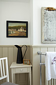 Bathroom with moisture-resistant reeded panelling walls antique mirror with foxed glass and jug on table under artwork 