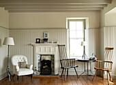 Der warme Grauton der getäfelten Wände des Wohnzimmers bildet die Kulisse für walisische Stühle im Folklorestil, die neben einem neu gepolsterten viktorianischen Pantoffelstuhl und Schmiedeeisen im Utility-Stil stehen
