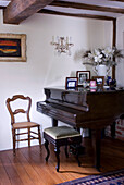 baby grand piano and piano stool in cottage with wooden floorboards
