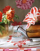 Vase mit Blumen auf Tischtuch mit Blumendruck