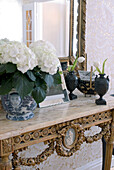 Blumen in Porzellanvase auf dem Tisch mit Spiegel dahinter