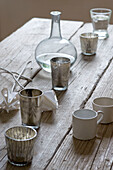 Cups candles and decanter on wooden dining room table