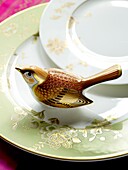 Detail of patterned tableware with ceramic bird