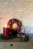 Lit candle and wreath of pinecones with gift wrapped presents Wiltshire
