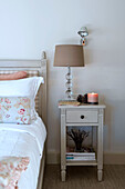 Lamp on bedside table with floral patterned cushion