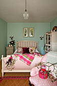 Folded bed linen in storage cupboard Pink checked blanket with mistletoe in green pastel bedroom
