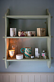 Perfumes and lit candles on wall mounted shelf unit