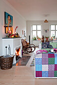 Patchwork quilt over sofa at open fire with rocking chair in Odense living room