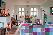 Patchwork quilt in Odense living room with lit fire and uncurtained windows