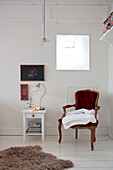 Sessel unter quadratischem Spiegel mit Beistelltisch und Stickerei in einem Schlafzimmer in Odense