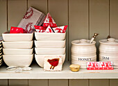 Honey and jam pots on shelf with ceramic bowls and Christmas cards in London home