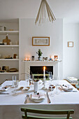 Lit candle on dining table in London home with recessed shelving