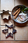 Star shaped biscuit cutters and cinnamon sticks in a metal tin