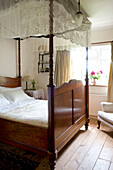Lace canopy on wood four poster bed in Devon home