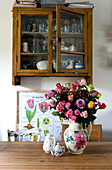 Küchentisch mit Glaswandschrank im Vintage-Stil und Schnittblumenvase