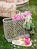 Korb mit Blumen und einem Paar Pantoffeln in einem Garten