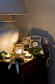 Beleuchtete Teelichter und ein Wählscheibentelefon auf einem Seitenelement eines Londoner Hauses UK