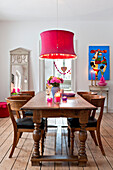 PInk ceiling light hangs above wooden dining table in modern Odense family home Denmark