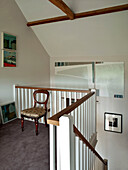 Antiker Stuhl und moderne Kunst im Treppenhaus eines Familienhauses in Suffolk, England, UK