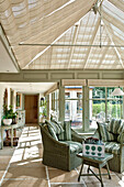 Matching chairs with striped green cushions in shaded sunroom of Canterbury home England UK