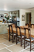 Wooden dining table and chairs in open plan flagstone kitchen of Canterbury home England UK