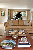 Grand piano and two seater sofa with coffee table and books in Canterbury home England UK
