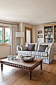 Korb auf geschnitztem Couchtisch mit Sofa und Bücherregal im Wohnzimmer eines Hauses in Canterbury England UK