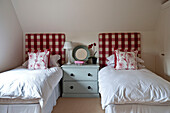 Rot und weiß karierte Kopfteile mit bemalter Truhe in einem Zweibettzimmer in einem Haus in Canterbury, England, UK