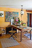 Arbeitstisch und Kunstwerke in einem ockerfarbenen Raum in einem Haus in Großbritannien