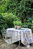 Wrought iron chairs at table with leaf motif cloth in garden of London home UK