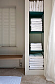 Folded white towels on storage shelves in bathroom of West London townhouse England UK