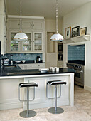Bar stools at breakfast bad in open plan West London townhouse kitchen England UK