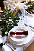 Christmas cracker on place setting on dining table in rural Suffolk home England UK