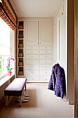 Purple coat with built-in storage unit in dressing room of rural Suffolk home England UK