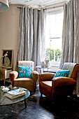 Vintage leather armchairs in bay window of London home, UK