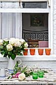 Weiße Rosen auf dem Gartentisch eines weiß getünchten Hauses in London, UK