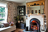 Gilt mirror above lit fire in living room of Walberton home, West Sussex, England, UK