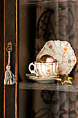 Cup and saucer in glass fronted cabinet in Walberton home, West Sussex, England, UK