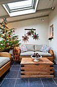 Korbsofa und hölzerner Couchtisch mit Weihnachtsbaum im Wintergartenanbau eines Hauses in Walberton, West Sussex, England, UK
