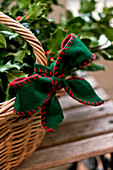 Green felt ribbon on basket with holly in Walberton home, West Sussex, England, UK