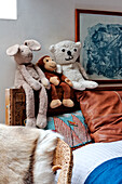 Soft toys on carved wooden headboard in bedroom of Forest Row family home, Sussex, England, UK