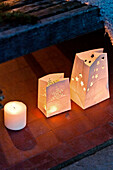 Lit candles in paper bags on terracotta doorstep of Forest Row family home, Sussex, England, UK