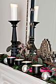 Tealights and leaves with silver baubles on mantlepiece in Paris apartment, France