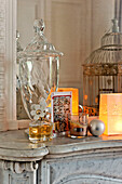 Antique glassware and bird cage with perfume bottle on marble fire surround in Paris apartment, France