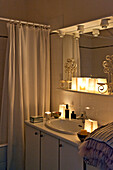 Lit candles on shelf above wash basin in Paris apartment, France