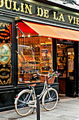 Bicycle parked on pavement outside delicatessen in Paris, France