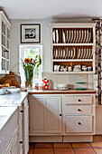 Cut flowers and plate rack in white fitted kitchen of Hertfordshire home, England, UK