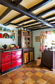 Colourful crockery with red oven in beamed kitchen of Essex home, England, UK