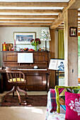 Piano and chair in beamed living room of Essex home, England, UK