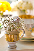 Artificial bird and cut spring blossom in milk jug, Essex home, England, UK